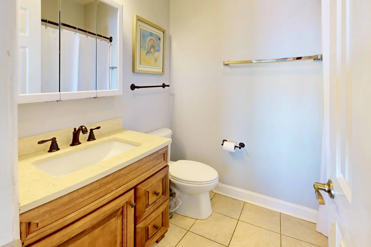 A well-appointed bathroom with a vanity and sink, framed artwork, and a serene, uncluttered atmosphere. The space is practical yet inviting, ideal for personal routines and relaxation.